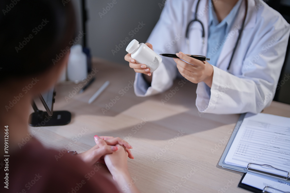 Fototapeta premium Asian psychologist women showing pills bottle to explaining medicine and prescription to female patient while giving counseling to explaining about mental health therapy to female patient in clinic