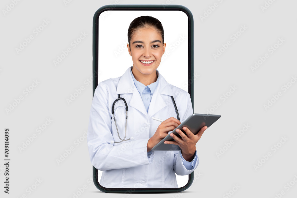 An amiable female doctor with a digital tablet smiles warmly, framed within a smartphone An amiable female doctor with a digital tablet smiles warmly, framed within a smartphone