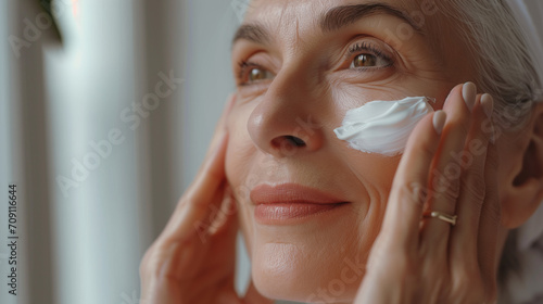 Beautiful senior woman applying cream on her face Facial care Reducing or anti-aging youthful face