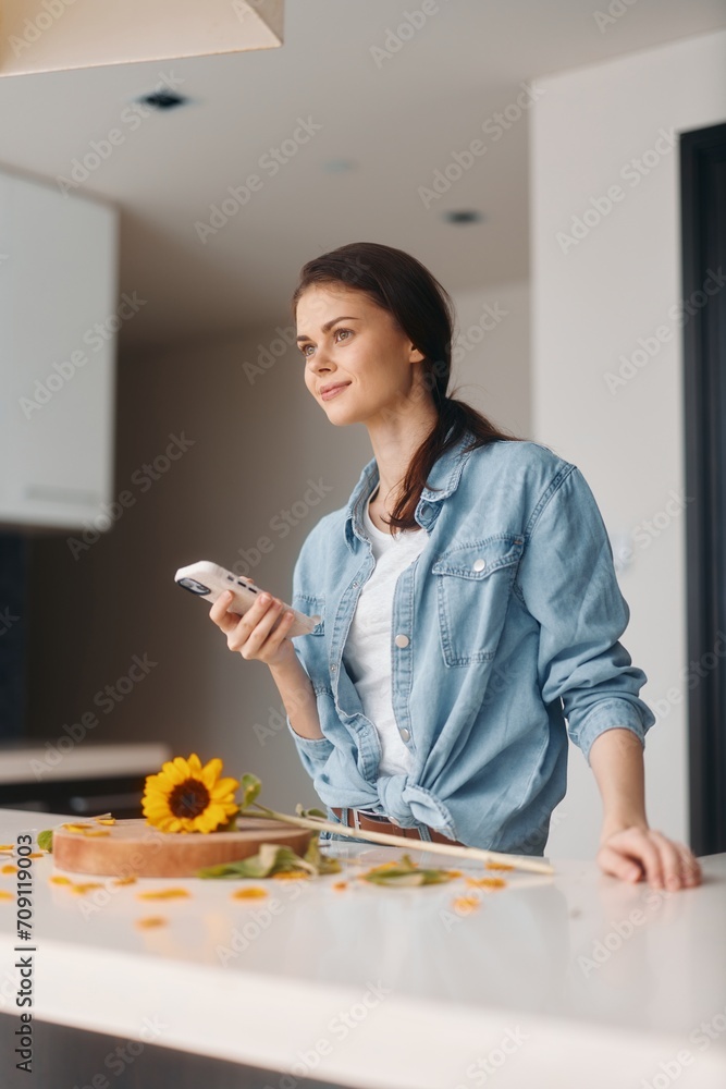 Young Caucasian Woman in a Modern Kitchen, Holding a Smartphone and Enjoying a Healthy Breakfast Young Caucasian Woman in a Modern Kitchen, Holding a Smartphone and Enjoying a Healthy Breakfast