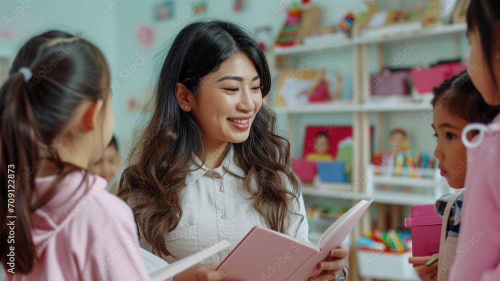 The young brunette woman teacher is reading a book to children during a lesson at a childcare center or school. The young brunette woman teacher is reading a book to children during a lesson at a childcare center or school.