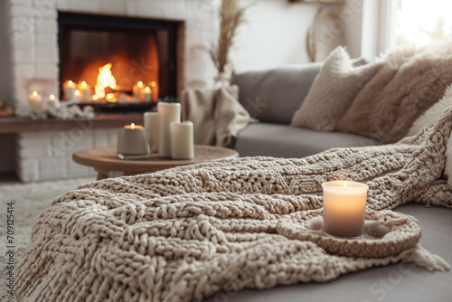 Beige Chunky Knit Throw Draped over a Grey Sofa, Coffee Table Adorned with Candles Near the Fireplace - A Scandinavian Farmhouse Hygge Home Interior Design, Creating a Warm and Inviting Winter Atmosph