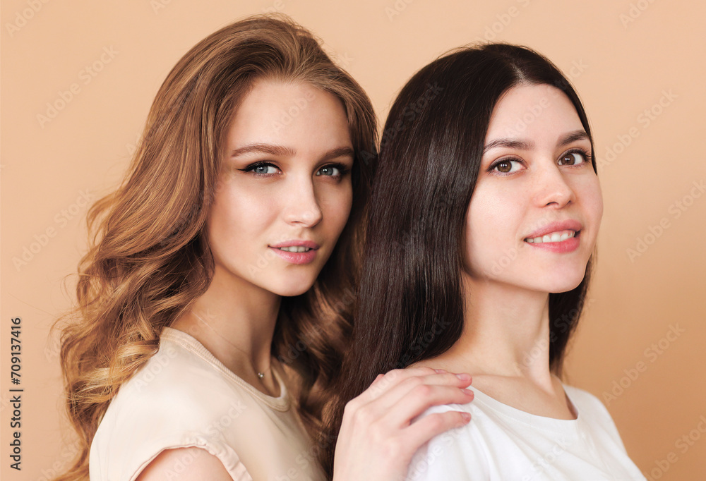 Two beautiful multicultural young women over beige background Two beautiful multicultural young women over beige background