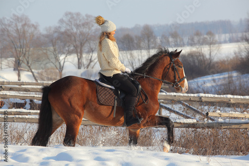 Girl galloping on horse in snowing ranch
