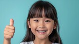 Asian girl in braces smiles and shows thumbs up. Medical orthodontic treatment braces for a beautiful smile
