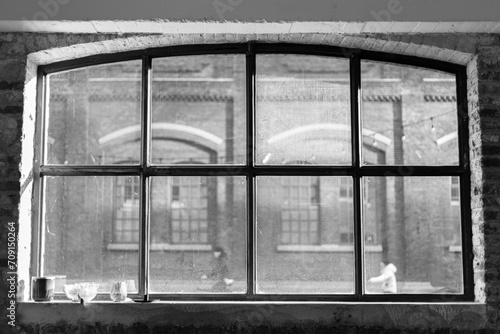 View through an old factory window frame in an industrial setting with cyclists out of focus in the background.