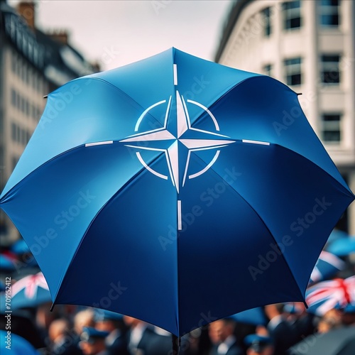 Blue umbrella with a NATO symbol against the background of a gathered crowd of people in the city.  photo
