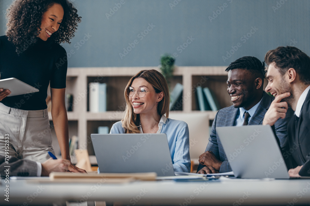 Happy group of business people discussing strategy during team meeting at the office desk together Happy group of business people discussing strategy during team meeting at the office desk together