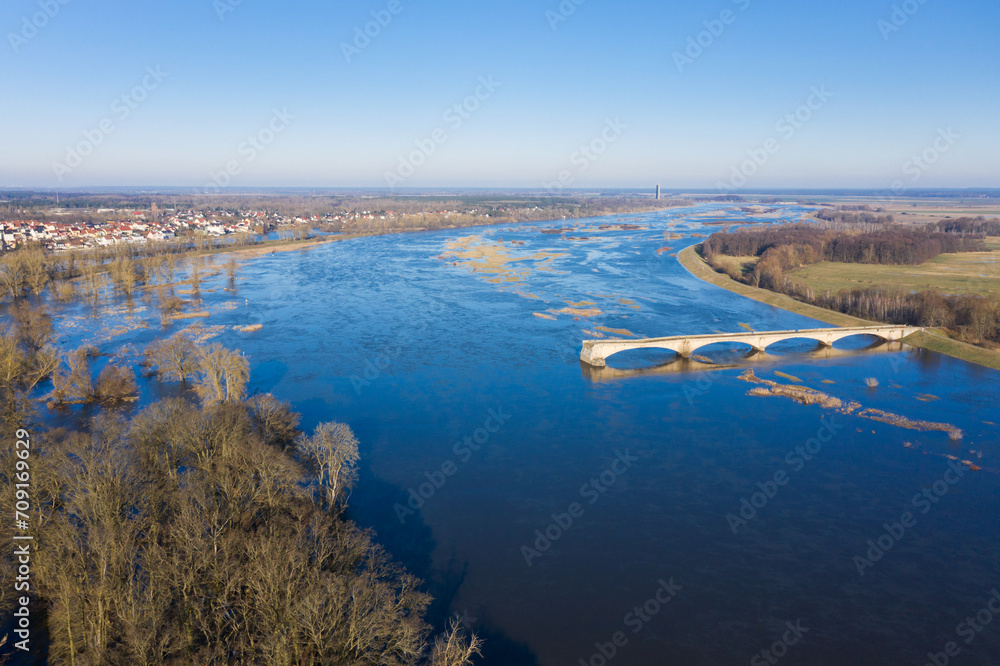 Aerial view of river flooding in front of a city with a demolished bridge