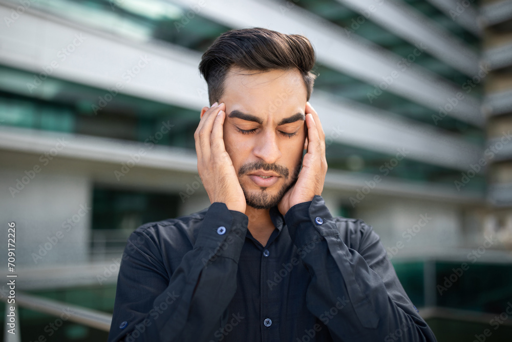 Obraz premium Portrait of stressed middle eastern businessman suffering from headache outside