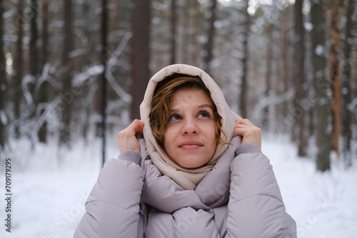 Photos A young woman stands against a background of fir trees under a snowy forest in winter