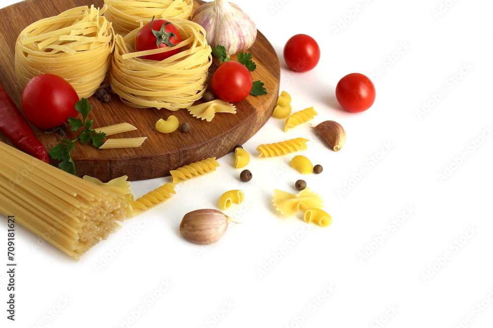 A round wooden cutting board with nest-shaped pasta and vegetables lies on a white background. A round wooden cutting board with nest-shaped pasta and vegetables lies on a white background.