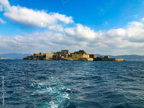 Gunkanjima: A serene seascape encircles the abandoned remnants of Japan's once-thriving Hashima coal mine. Sunlight dances on the waves, framing the island's haunting silhouette.