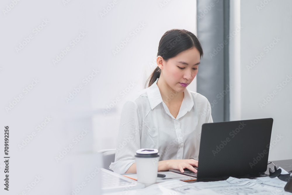 Portrait of a beautiful confident businesswoman using a laptop computer sitting in a modern office. Smiling Asian freelancer working online from home. Portrait of a beautiful confident businesswoman using a laptop computer sitting in a modern office. Smiling Asian freelancer working online from home.