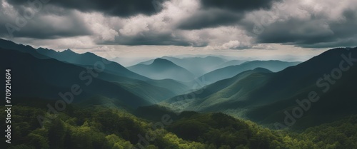 Amazing wild nature view of layer of mountain forest landscape with cloudy sky.  © Adi