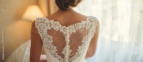 Stunning sleeveless wedding gown adorned with lace and buttons, showcasing the beautiful bride's bare back.