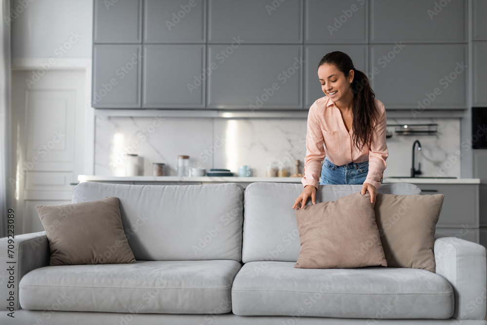 © Prostock-studio - Woman arranging pillows on couch in a clean, modern home © Prostock-studio - Woman arranging pillows on couch in a clean, modern home