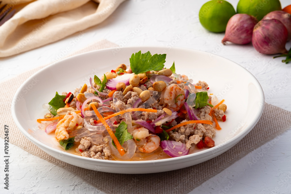 Spicy Glass Seaweed noodle Salad with Minced Pork (yum sen kaew) is a type of Thai salad made with clear Kelp noodle and meat in white plate