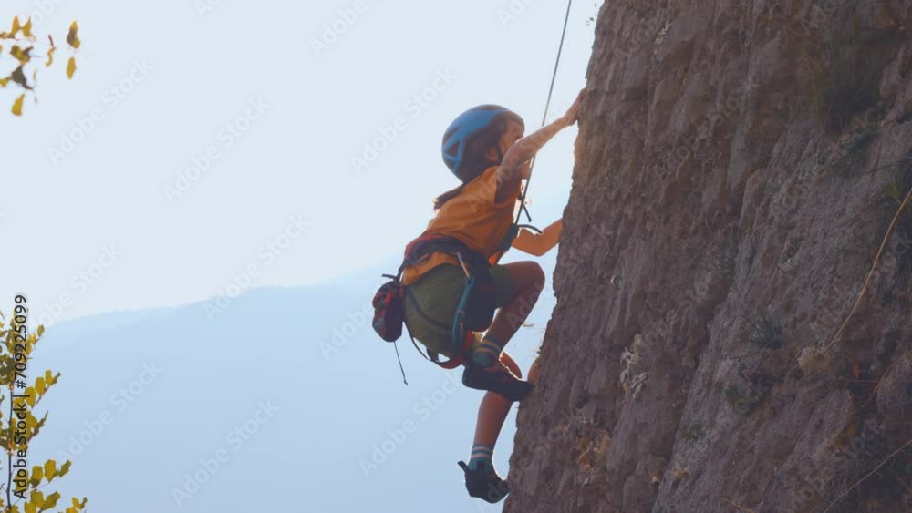 The child is climbing on a natural terrain. A boy climbs a rock on a background of mountains. Extreme hobby. Athletic kid trains to be strong. Rock climbing safety.
The child is climbing on a natural terrain. A boy climbs a rock on a background of mountains. Extreme hobby. Athletic kid trains to be strong. Rock climbing safety.