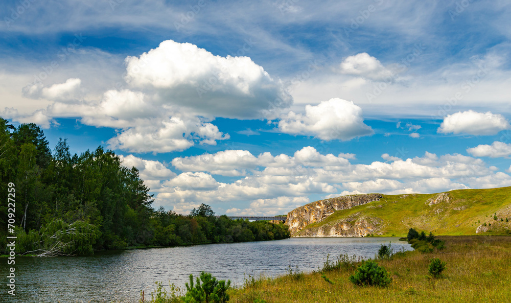 Fototapeta premium A beautiful view of nature of Urals, Russia. Mountains, mountainous terrain, river, pine and spruce forest, clouds. Summer landscape.
