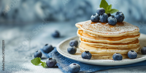 Fluffy tasty pancakes with blueberries on a plate in bright daylight. Rustic shabby chic feel. Pancake Day. Banner with empty space for text. photo
