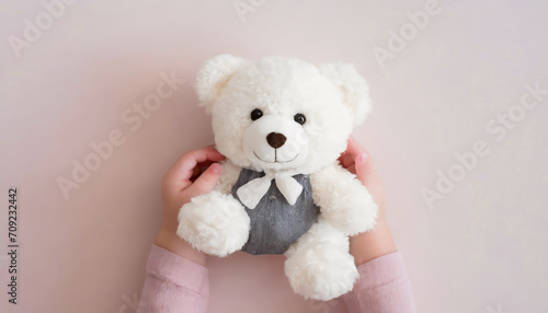 Baby girl hands holding, smiling white teddy bear on light pink background © Loliruri