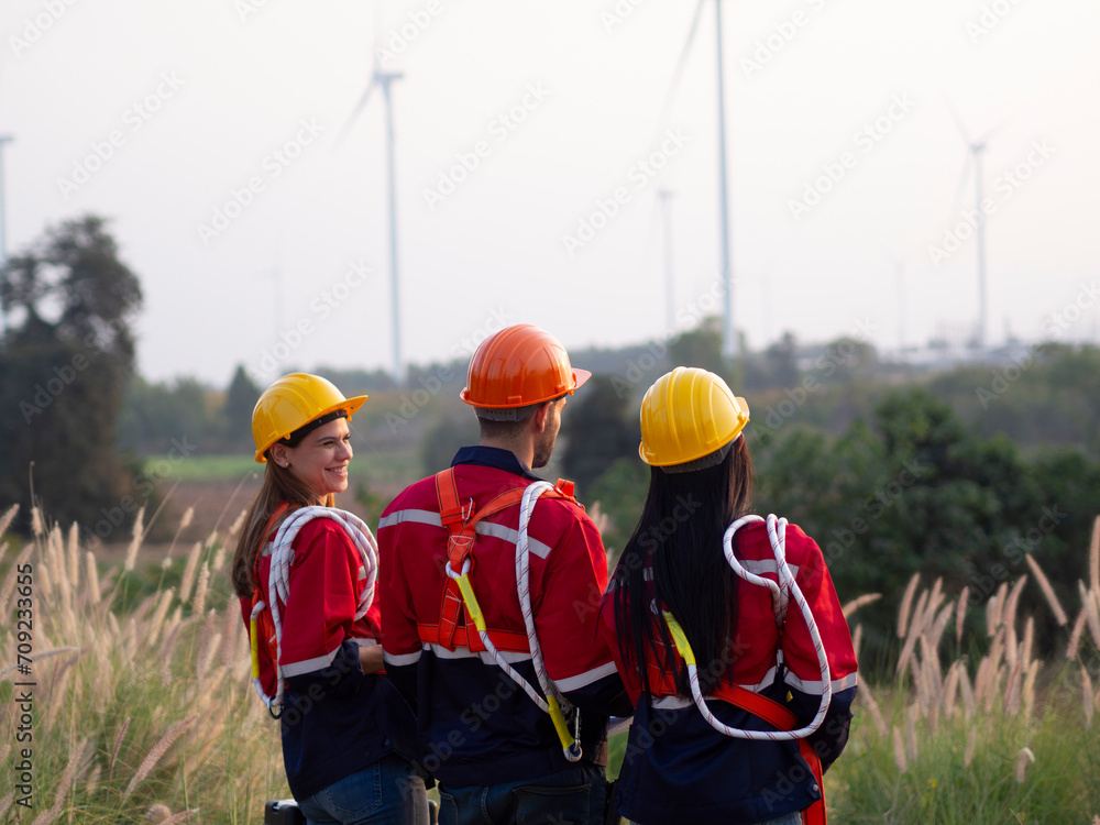 Group of maintenance engineers preparing and planning inspection of wind turbines, holding tablets, looking at wind turbines Group of maintenance engineers preparing and planning inspection of wind turbines, holding tablets, looking at wind turbines