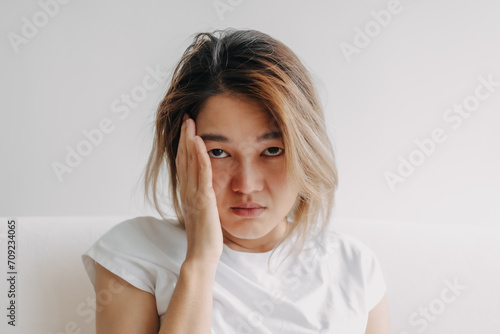 Close up headshot of headache hangover Asian woman with hand covering her head.