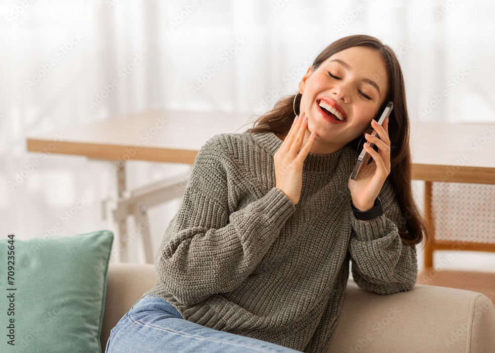 Joyful lady talking on phone and laughing, home interior Joyful lady talking on phone and laughing, home interior