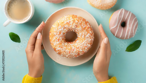 Top view of hands taking tasty sugary donut ready to eat on pastel background photo