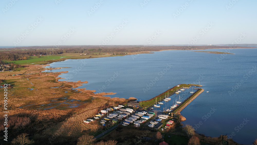 Fototapeta premium Tranquil scene of a serene lake with a sandy beach and a pier extending into the water.