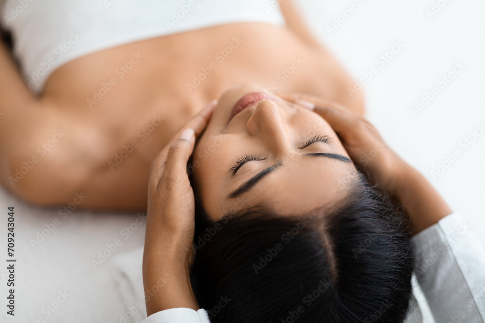 Masseuse making relaxing face massage for young beautiful indian lady Masseuse making relaxing face massage for young beautiful indian lady