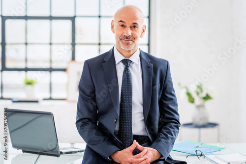 Mid aged businessman standing at office desk photo