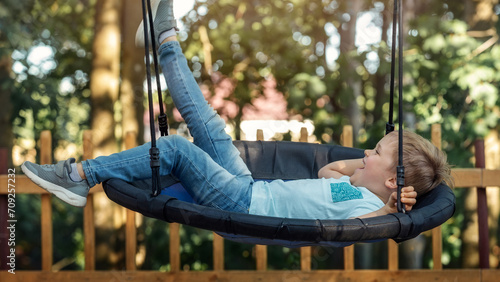 Relaxing in a hammock. A cheerful little boy swings with his leg up photo