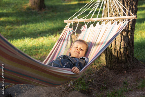 Child swinging and relaxing in hammock. Child summer holidays healthy lifestyle and outdoors leisure activity