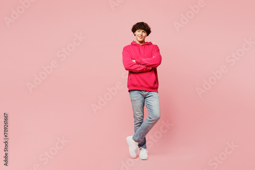 Full body fun smiling happy young Caucasian man he wears hoody casual clothes hold hands crossed folded look camera isolated on plain pastel light pink background studio portrait. Lifestyle concept.