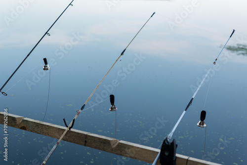 Fishing rod with a stretched fishing line and bells on the background of the water. Background on the theme of recreation on fishing.