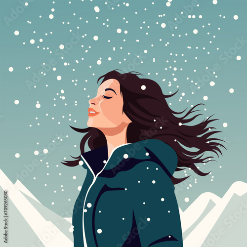 A beautiful girl in warm winter clothes catches snowflakes.
