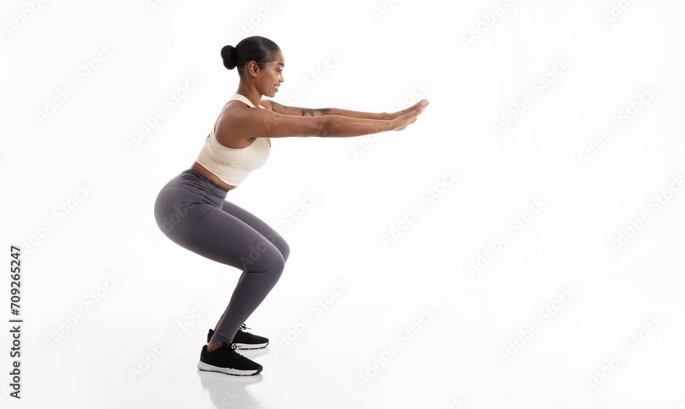 Obraz premium Black Fitness Woman Doing Squat Exercise Over White Studio Background