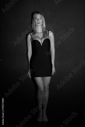 Black and white low key portrait of pretty woman in short dress