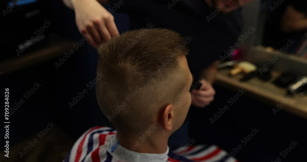 Barber trims hair in temporal area of man client head Barber trims hair in temporal area of man client head
