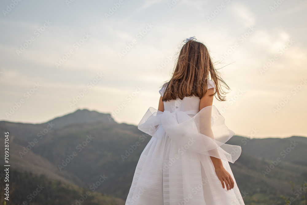 Girl with first communion dress observing the mountain