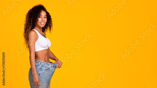 black woman wearing too large jeans showing slimmed body, studio photo