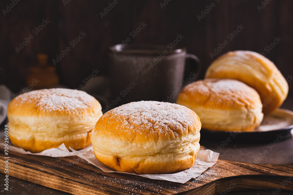 Sweet donuts with powdered sugar filled with boiled condensed milk on a plate