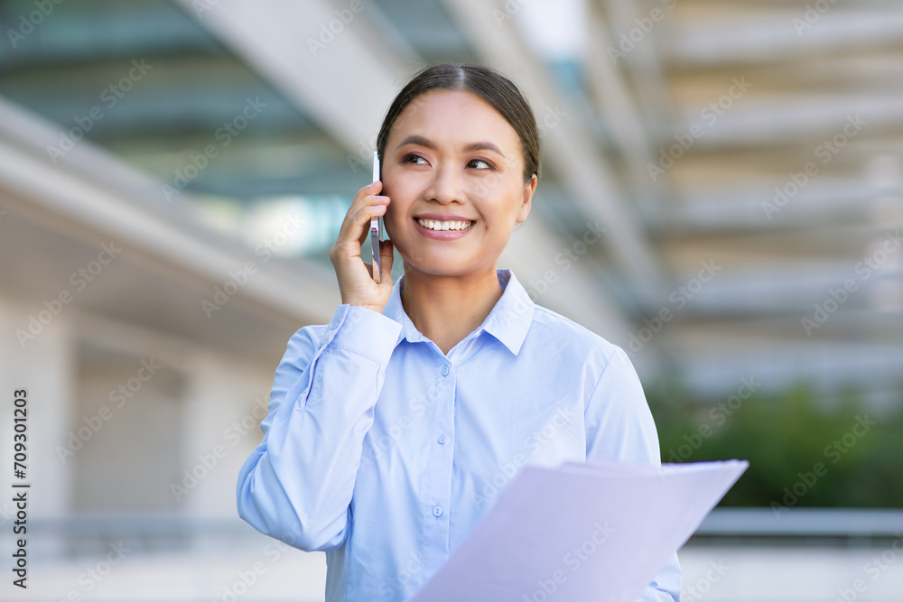 Young Chinese manager lady using phone making business calls outdoors Young Chinese manager lady using phone making business calls outdoors