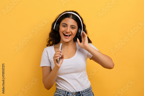Joyful pretty young indian woman singing songs, karaoke app
