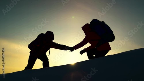 Teamwork of business people. Go towards your goal. Team of businessmen victory. Travelers climb one after another on rock Climbers silhouettes stretch their hands to each other climbing to top of hill photo