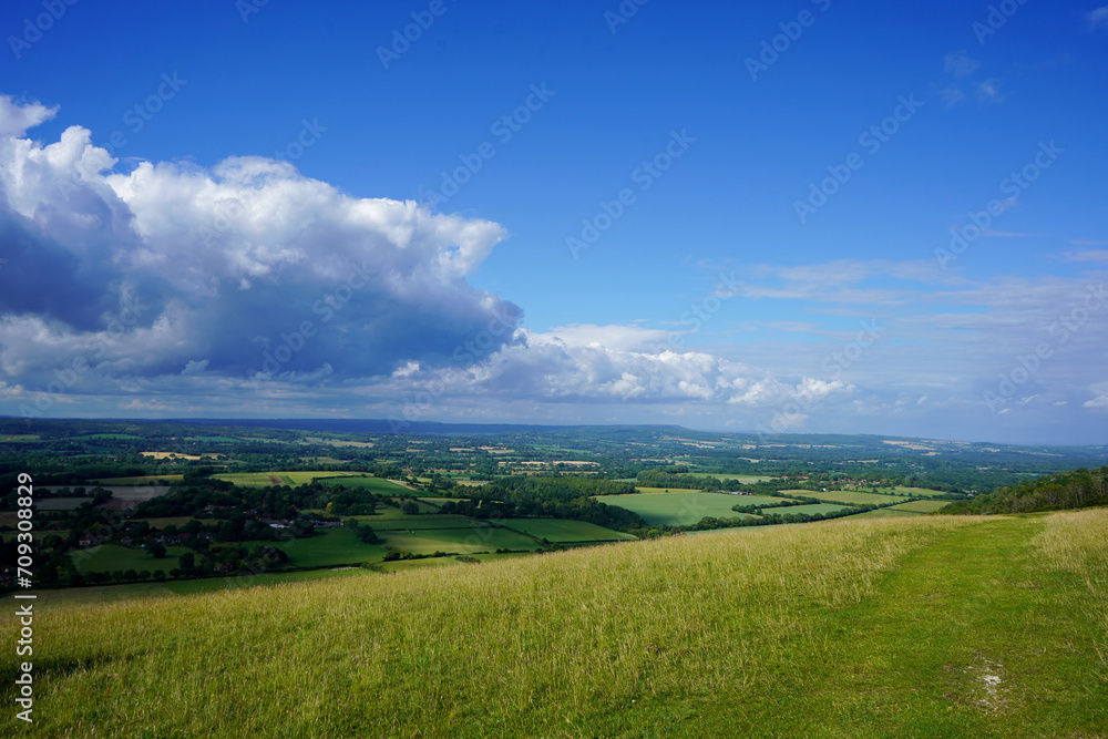 Views over countryside farm fields with clouds in blue sky in the summer