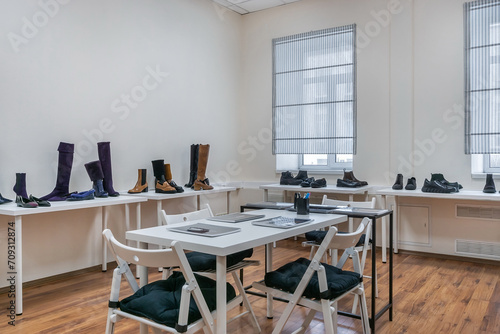 A table for visitors in a bright showroom with shoes on the shelves. © alhim