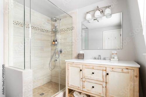 Fototapeta Naklejka Na Ścianę i Meble -  A bathroom with a wood cabinet, white marble countertop, and a brown tiled walk-in shower. No brands or logos.
